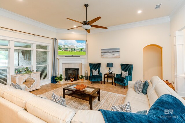 living room featuring plenty of natural light, a tiled fireplace, ceiling fan, and crown molding