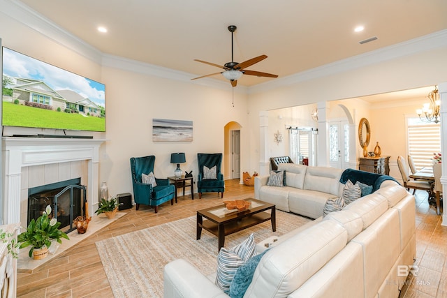 living room featuring ornamental molding, light hardwood / wood-style flooring, a fireplace, and ceiling fan with notable chandelier