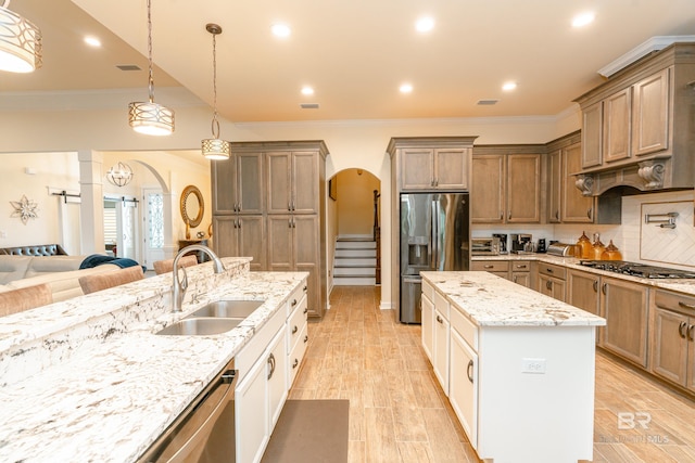 kitchen with decorative light fixtures, sink, stainless steel appliances, and crown molding