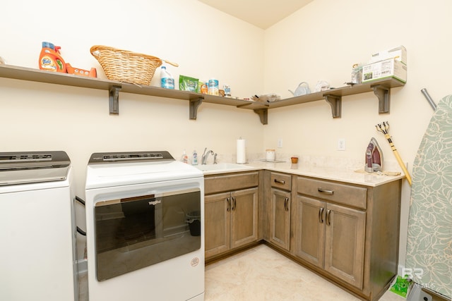 clothes washing area featuring sink, washing machine and clothes dryer, cabinets, and light tile floors