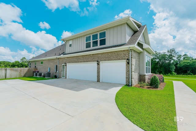 view of front of property with a front yard, a garage, and central AC