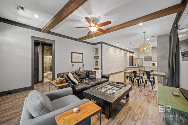 living room with beamed ceiling, hardwood / wood-style flooring, and ceiling fan with notable chandelier