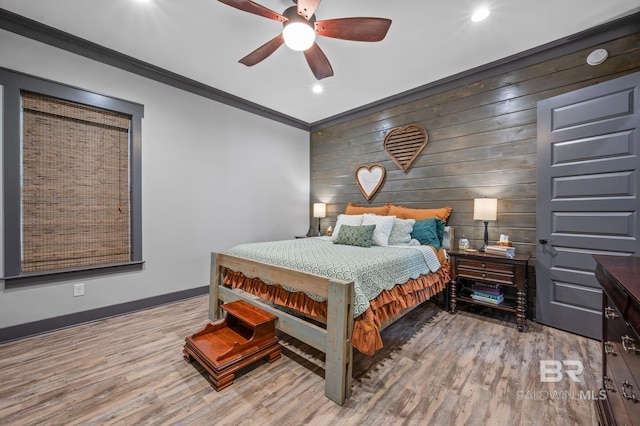 bedroom featuring ceiling fan, wood walls, light wood-type flooring, and ornamental molding