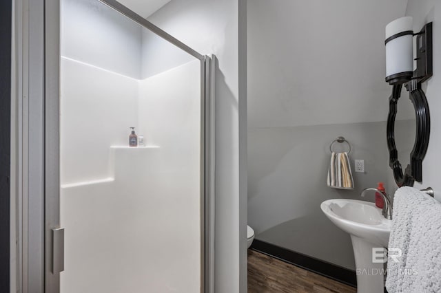 bathroom with a shower with shower door, hardwood / wood-style floors, and toilet