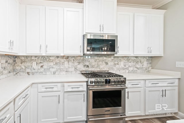 kitchen with appliances with stainless steel finishes, backsplash, hardwood / wood-style flooring, and white cabinetry