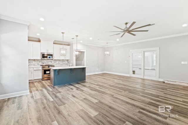 kitchen with white cabinets, an island with sink, stainless steel appliances, and light hardwood / wood-style floors