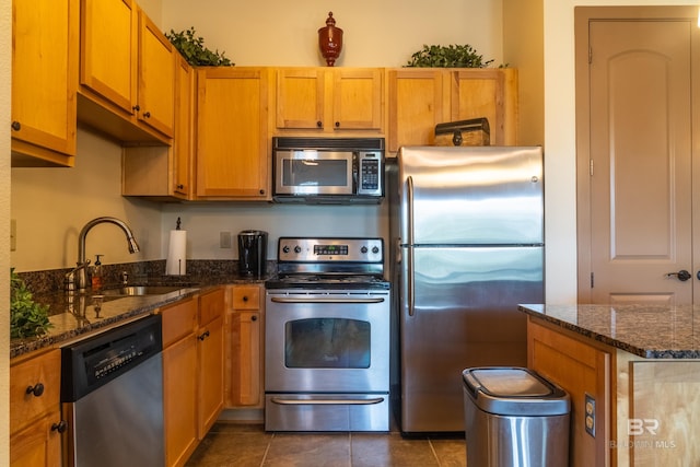 1430 Regency Rd Unit J302, Gulf Shores, AL 36542 - kitchen with stainless steel appliances, a sink, dark tile patterned floors, dark stone countertops, and brown cabinetry