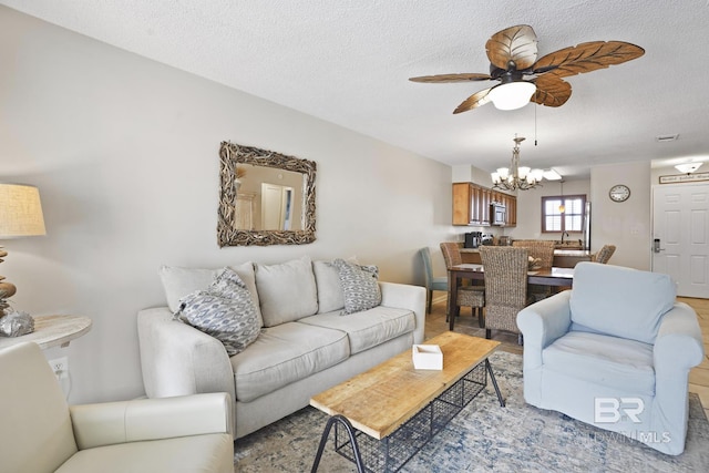 living room featuring sink, ceiling fan with notable chandelier, a textured ceiling, and light hardwood / wood-style floors