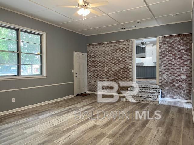 unfurnished living room featuring ceiling fan, wood-type flooring, and a drop ceiling