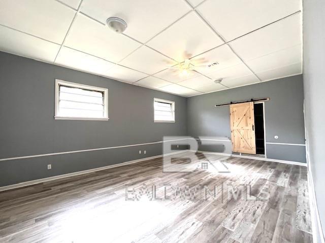 interior space featuring a paneled ceiling, a barn door, and hardwood / wood-style floors