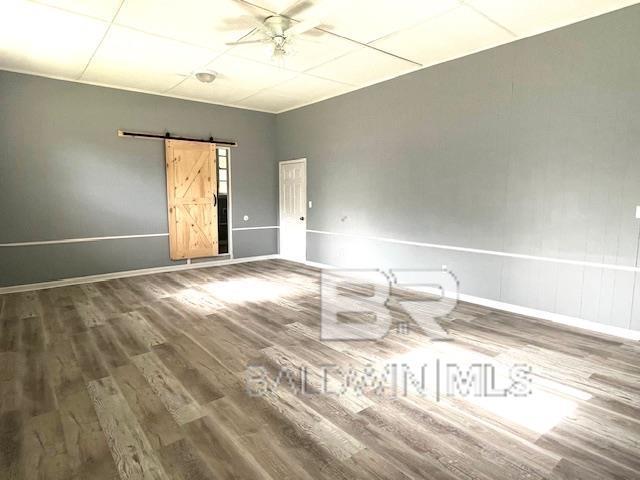 spare room with hardwood / wood-style flooring, a barn door, and ceiling fan