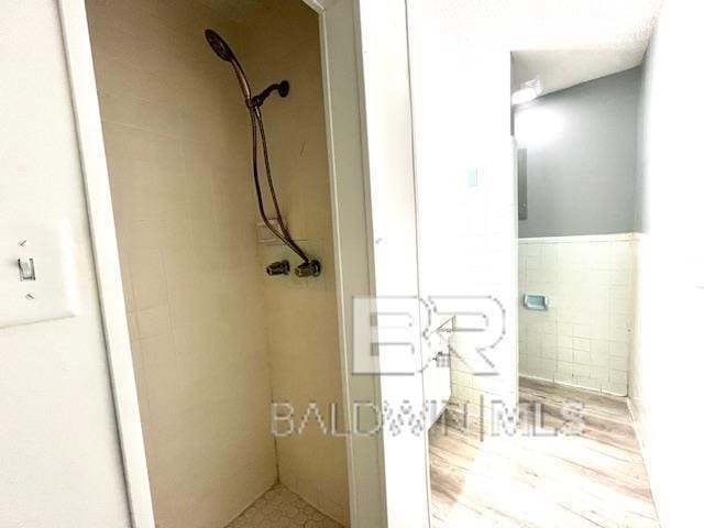 bathroom featuring a tile shower and tile walls