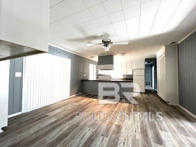 kitchen with ceiling fan, refrigerator, dark hardwood / wood-style floors, and kitchen peninsula