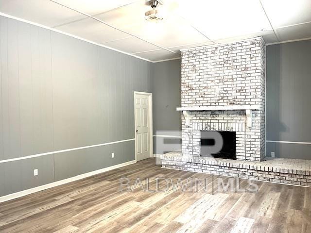 unfurnished living room with hardwood / wood-style floors, crown molding, and a fireplace