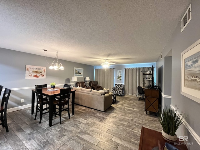 dining room featuring hardwood / wood-style flooring, ceiling fan with notable chandelier, and a textured ceiling