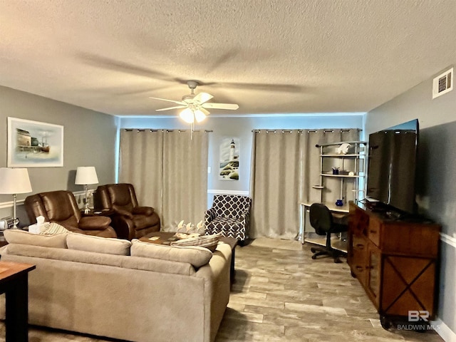 living room featuring ceiling fan, light hardwood / wood-style flooring, and a textured ceiling