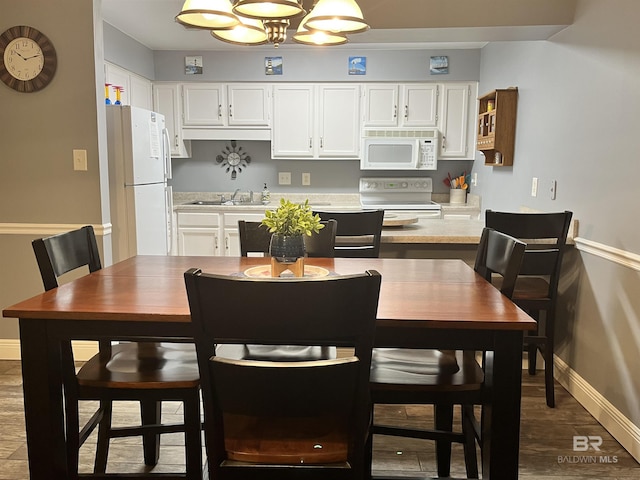 kitchen featuring white cabinetry, sink, white appliances, and wood-type flooring