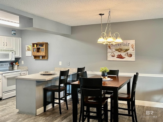 dining space featuring a notable chandelier, hardwood / wood-style flooring, and a textured ceiling