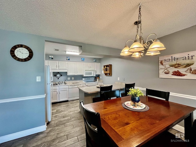 dining area featuring an inviting chandelier, sink, and a textured ceiling