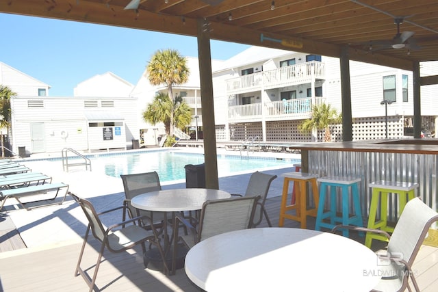 view of patio / terrace with a bar, ceiling fan, and a community pool