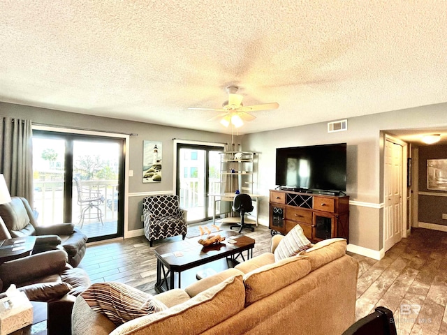 living room featuring hardwood / wood-style flooring, ceiling fan, and a textured ceiling