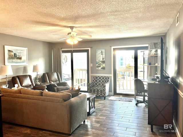 living room featuring ceiling fan, dark hardwood / wood-style flooring, and a textured ceiling