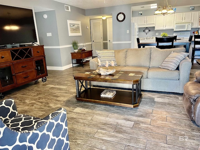 living room with a notable chandelier, hardwood / wood-style flooring, and a textured ceiling