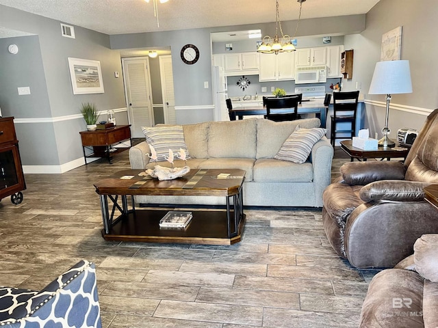 living room featuring an inviting chandelier, wood-type flooring, and a textured ceiling