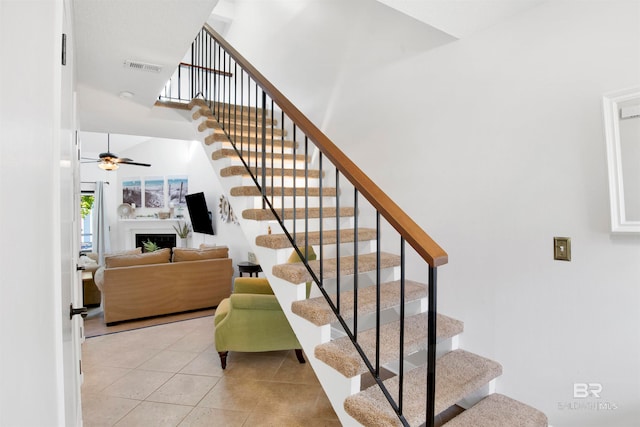 stairs with ceiling fan, a towering ceiling, and tile patterned flooring