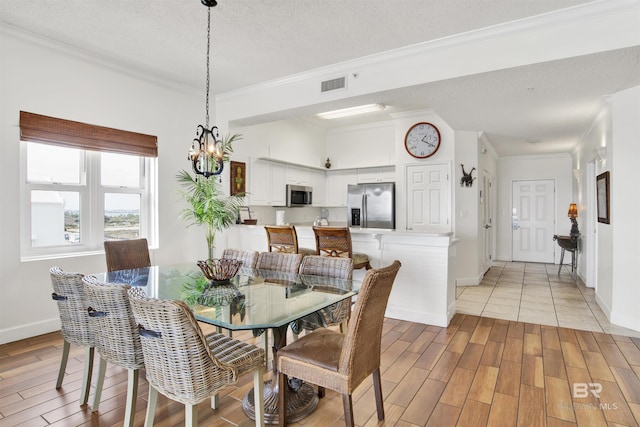 dining area featuring a textured ceiling, light hardwood / wood-style flooring, and ornamental molding