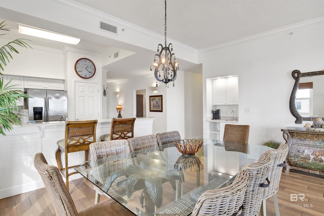 dining space with light hardwood / wood-style flooring, a chandelier, and ornamental molding