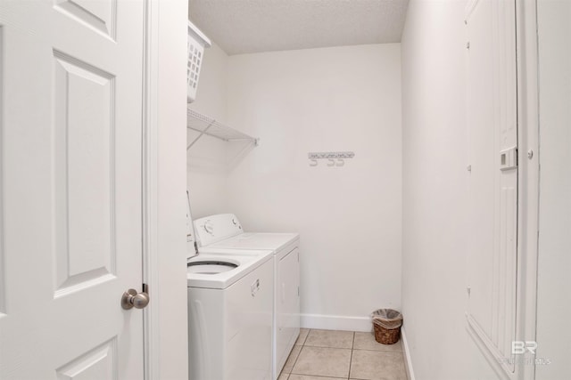 clothes washing area with washer and dryer, light tile patterned flooring, and a textured ceiling