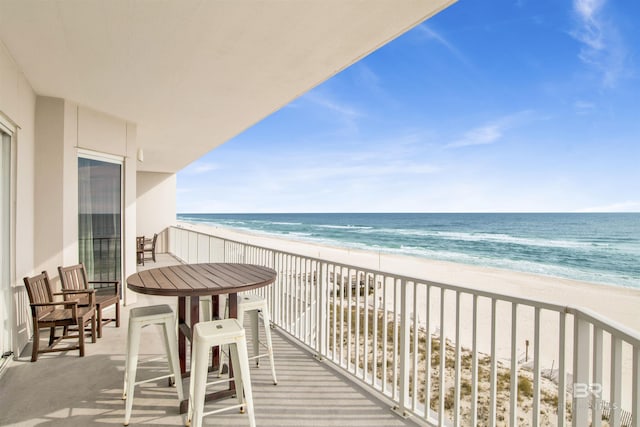 balcony featuring a view of the beach and a water view