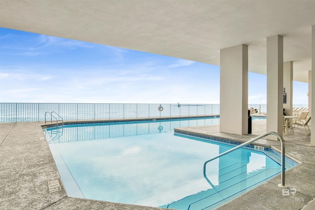 view of pool featuring a water view and a patio