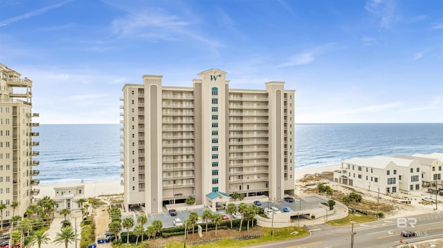 view of building exterior featuring a water view and a beach view