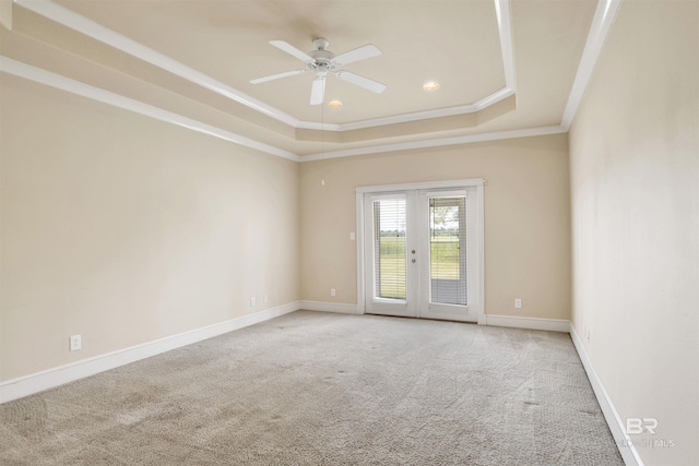 carpeted empty room featuring a raised ceiling, ceiling fan, french doors, ornamental molding, and recessed lighting