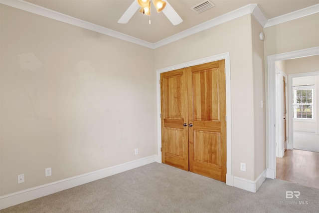 unfurnished bedroom with carpet flooring, crown molding, baseboards, a ceiling fan, and a closet