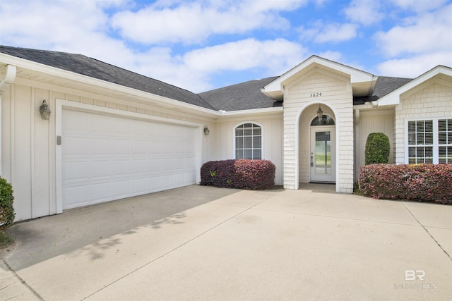 view of front of home featuring board and batten siding, concrete driveway, a shingled roof, and an attached garage