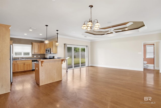kitchen featuring stainless steel appliances, a sink, ornamental molding, a breakfast bar area, and wood finished floors