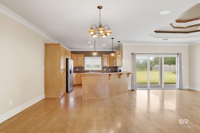 kitchen with stainless steel appliances, a kitchen bar, a chandelier, light wood finished floors, and a peninsula
