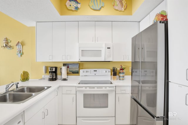 kitchen with white cabinets, white appliances, sink, and a textured ceiling