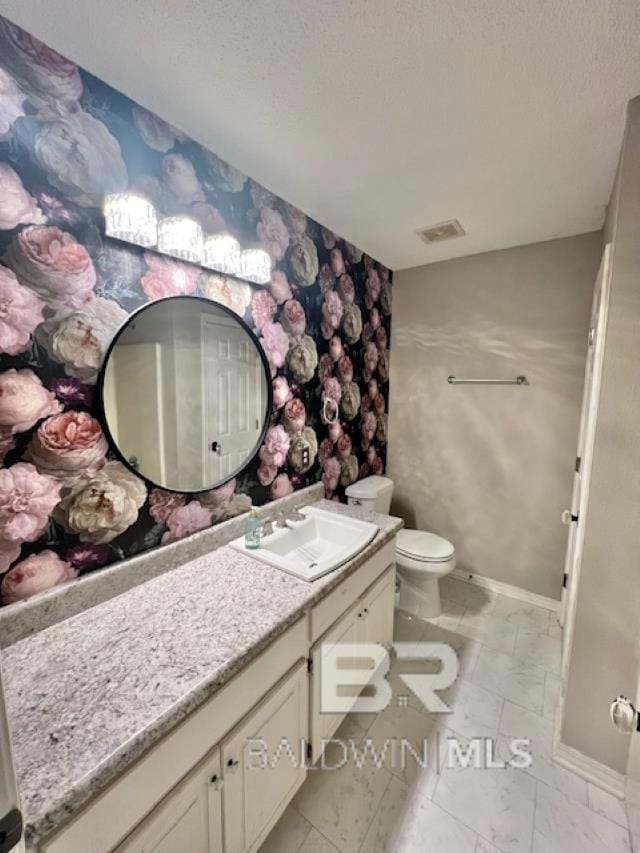 bathroom with vanity, a textured ceiling, and toilet