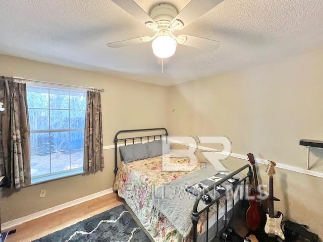 bedroom with ceiling fan, wood-type flooring, and a textured ceiling