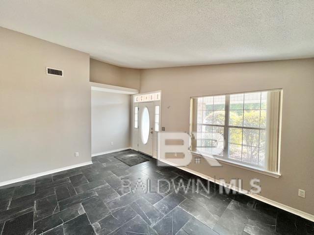 foyer entrance with lofted ceiling and a textured ceiling