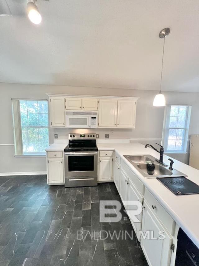 kitchen featuring stainless steel range with electric stovetop, sink, pendant lighting, and white cabinets