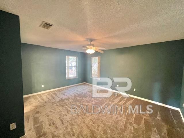 spare room featuring a textured ceiling, ceiling fan, and carpet