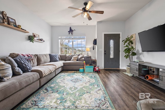 living area with baseboards, a ceiling fan, and dark wood-type flooring