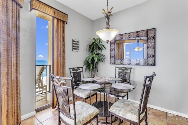 dining room with tile patterned floors, a water view, baseboards, and a healthy amount of sunlight
