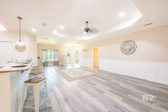 interior space featuring crown molding, a tray ceiling, light hardwood / wood-style floors, and ceiling fan