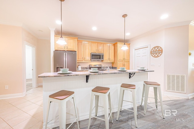 kitchen featuring stainless steel appliances, crown molding, hanging light fixtures, and a center island with sink